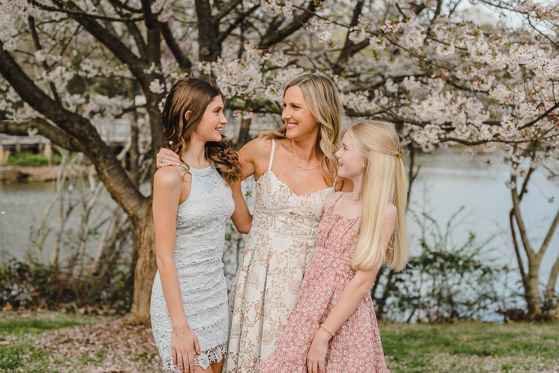 Mom standing in between her two daughters, laughing and smiling at each other